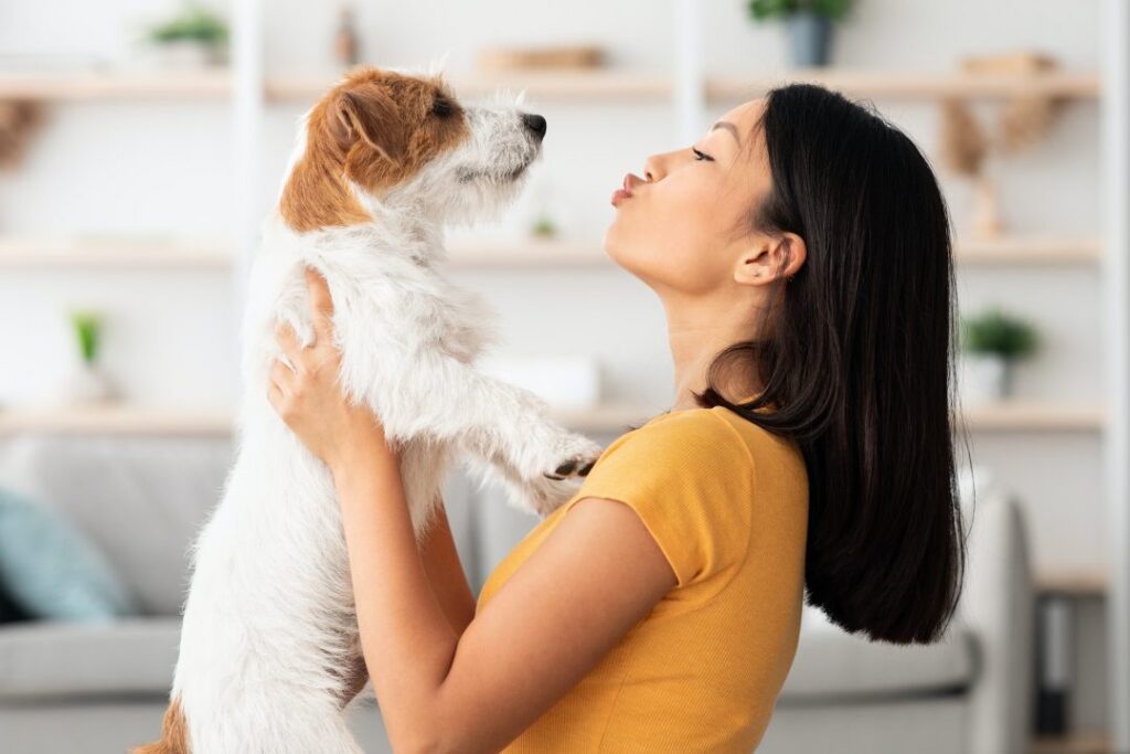 A woman smiling as she carries her small dog
